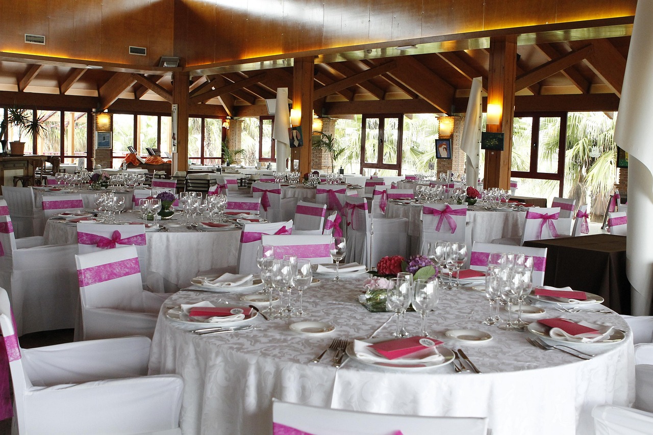  Image of a wedding reception hall, white table cloths and pink napkins.